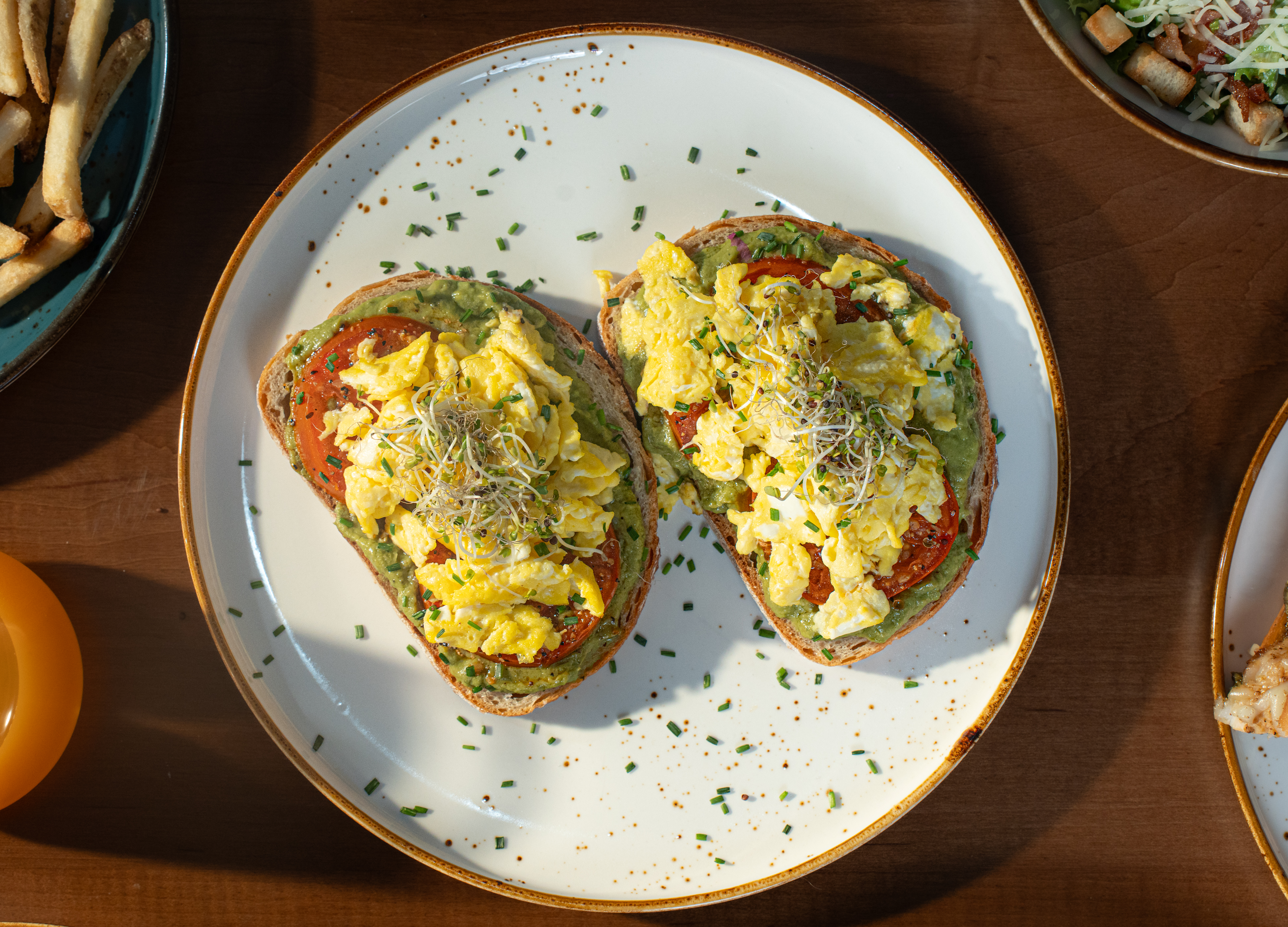 Solena Avocado Toast — Toasted sourdough topped with smashed avocado, roasted tomatoes, and scrambled eggs.
