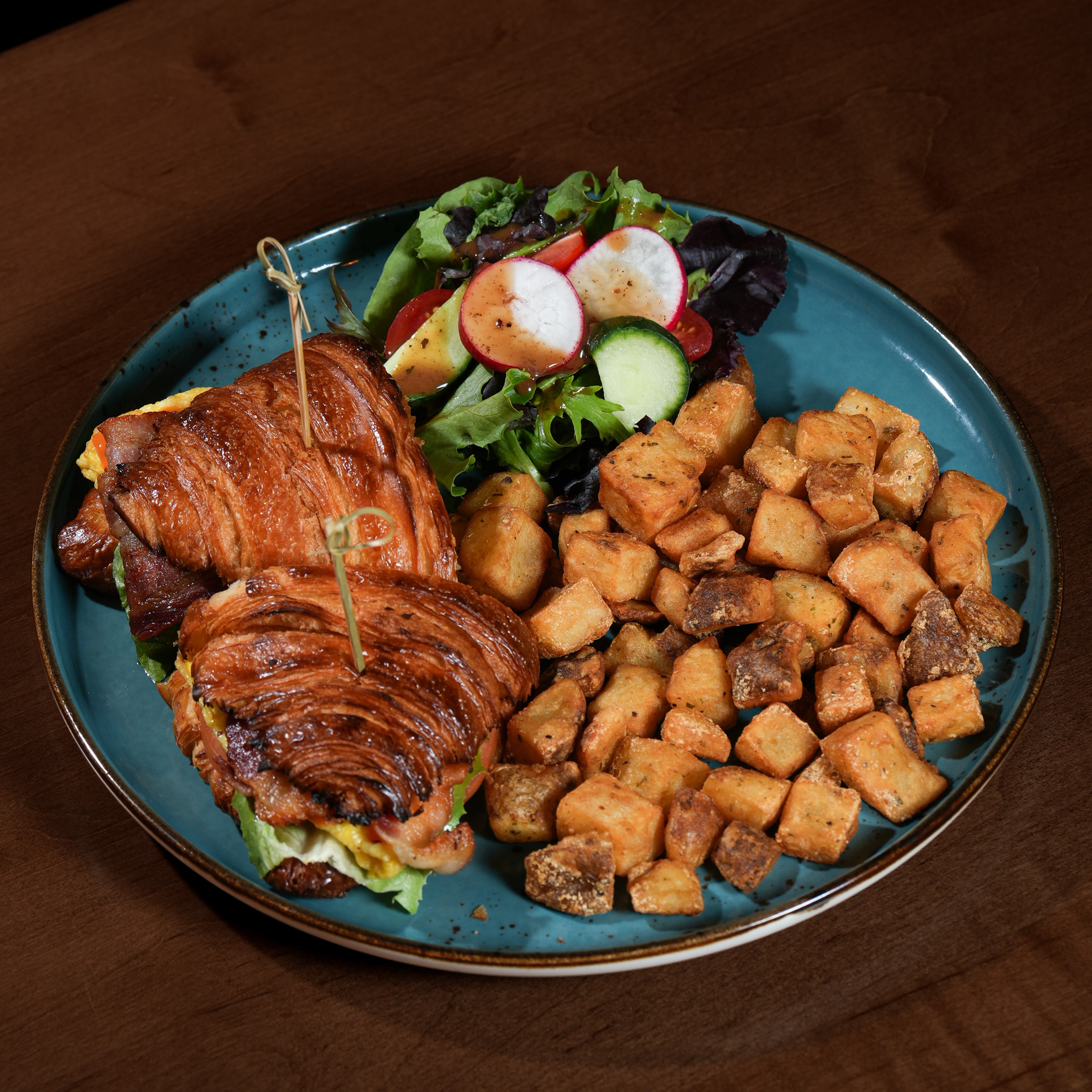Solena Croissant Sandwich — Fresh croissant with eggs, cheddar, bacon, lettuce, tomato, served with home fries and house salad. — Brunch Favourites at SOLENA Brunch & Bar in Corso Italia, Toronto