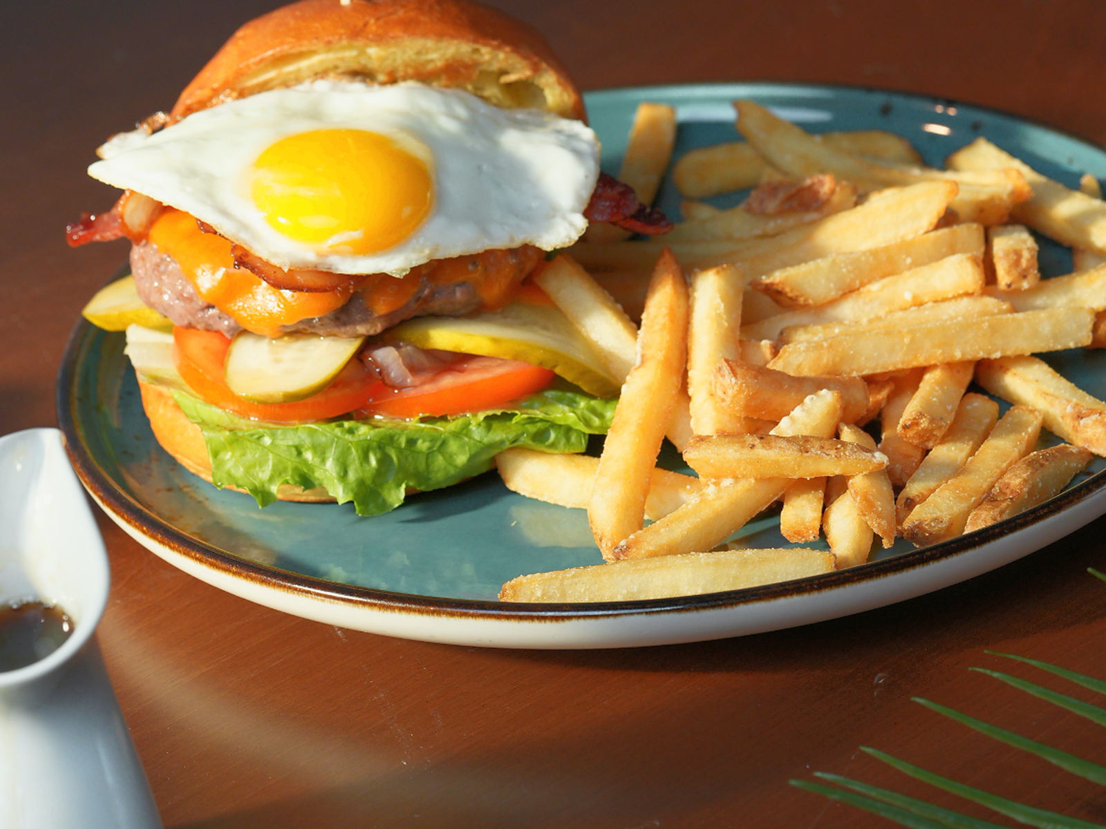 Solena Signature Burger — House beef patty with bacon, cheddar, sunny-side egg, lettuce, tomato, pickles, and caramelized onions. — Burgers at SOLENA Brunch & Bar in Corso Italia, Toronto
